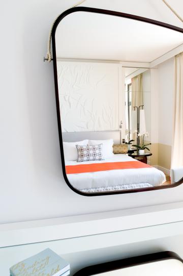 Ce grand miroir, évoquant un galet, est accroché au mur par des cordages et dissimule un écran de télévision © Royal Riviera Ce grand miroir, évoquant un galet, est accroché au mur par des cordages et dissimule un écran de télévision © Royal Riviera