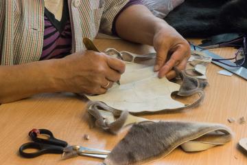 Une couturière découpe des morceaux de peau de phoque pour assembler un teddy bear.
