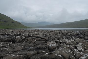 Les galets basaltiques à l’extrémité du lac de Leitisvtan, visible à l’arrière-plan. Les galets basaltiques à l'extrémité du lac de Leitisvtan, visible à l'arrière-plan.